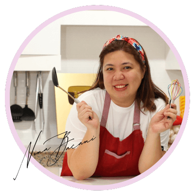 Nina Bacani smiling in a kitchen while holding cooking tools